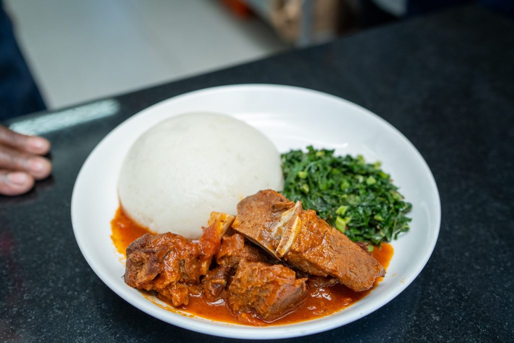 Plated sadza with beef stew and greens