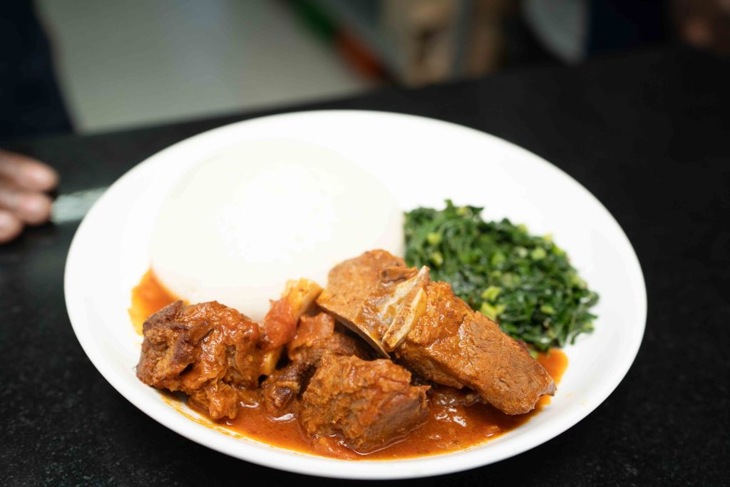 Plated goat stew with sadza and greens